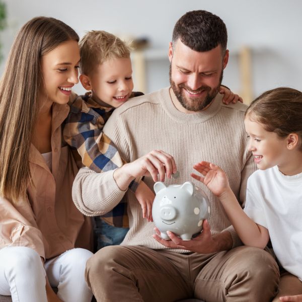 a family placing money into a piggy bank