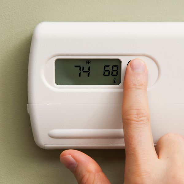 A person changing a thermostat degree