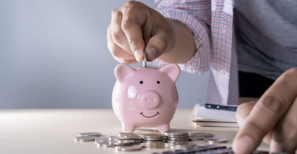 A person placing a coin into a piggy bank